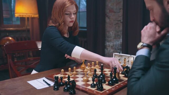 Two chess players man and woman play chess. Debut Accepted Queen's Gambit, King's Gambit, Philidor's Defense. Cinematic filming of a chess game. Antique chess board. This shot can be used for films
