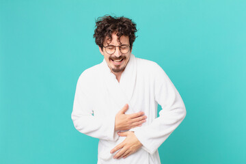 young man wearing bathrobe laughing out loud at some hilarious joke
