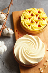 Delicious mini tarts yellow and white with nuts and custard on wooden cutting board. Assortment of delicious and colorful dessert, lemon curd tart, cream chocolate tart made by chef