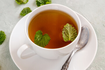 Fresh lemon balm tea in a white cup.