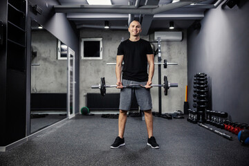 Fototapeta na wymiar A man exercising with a barbell gym. A photo of a fitness man in sportswear and good physical shape in an isolated indoor gym. Strength and motivation, sports, fitness goal, personal training