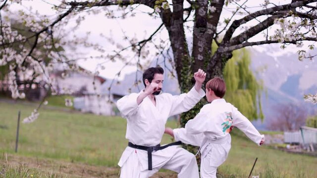 Karate training between dad and son near a cherry tree. Cinematic shot with 6k video.