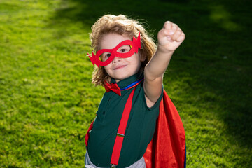 Brave boy in a superhero costume, wearing a red Cape and mask, held out his hand. Cute kid playing superhero. The concept of power and justice. - obrazy, fototapety, plakaty