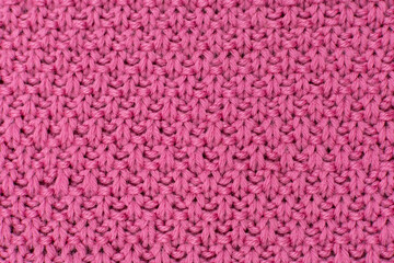 Pink knitted fabric pearl woolen background. The structure of the fabric with a natural texture. Fabric background. Knitted woolen background.
