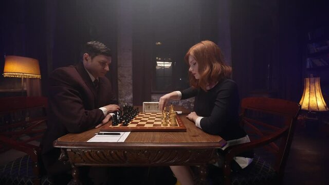 Two chess players man and woman play chess. Debut Accepted Queen's Gambit, King's Gambit, Philidor's Defense. Cinematic filming of a chess game. Antique chess board. This shot can be used for films
