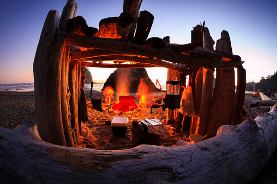 A camping group gathers wood and stokes their camp fire at sunset on Second Beach in Olympic National Park Washington.