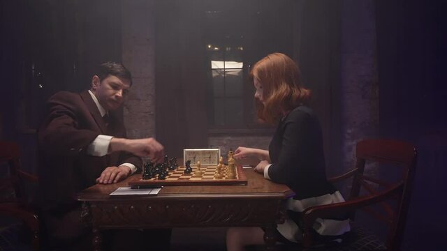Two chess players man and woman play chess. Debut Accepted Queen's Gambit, King's Gambit, Philidor's Defense. Cinematic filming of a chess game. Antique chess board. This shot can be used for films
