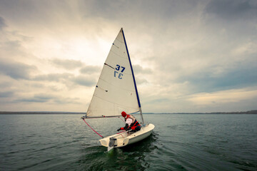 the yacht floats on the water against the backdrop of the cloudy sky and the sun