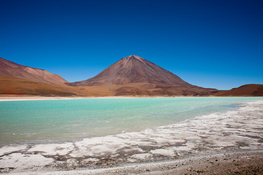 Laguna Verde sits at500' above sea level, below the000' Llicancabur Volcano deep in the Sud Lipez region of southwestern Bolivia. The green color of the water comes from the natural leaching of minerals (like arsenic) from the surrounding mineral-laden peaks of the Andes mountains.
