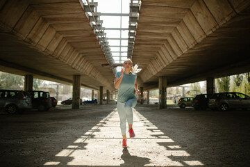 Beautiful woman running under bridge on the morning.