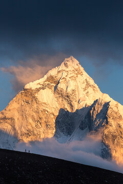 Two hikers on a ridge below Ama Dablam give scale to the massive peak in Nepal's Khumbu region.