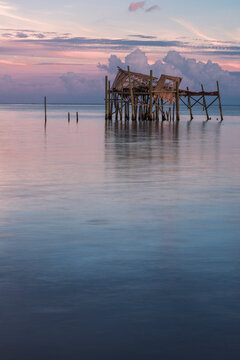 Cedar Key, FL: A weathered old shack stands alone in the gulf of Mexico during sunset