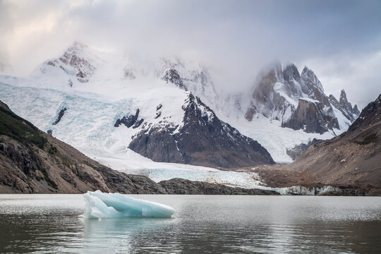Cerro Torre pokes through the clouds as a lone iceberg floats upon Laguna Torre -Los Glaciares National Park - Santa Cruz Province, Argentina