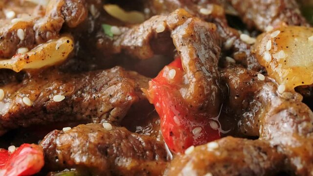 Stir fry Chinese pepper beef steak with onion, red and green bell pepper. rotating video.