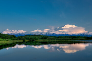 Sunset the first week of summer in Denali National Park, Alaska, casts a soft light on the summits of Mt. McKinley and the Alaska Range, reflecting in Reflection Pond.
