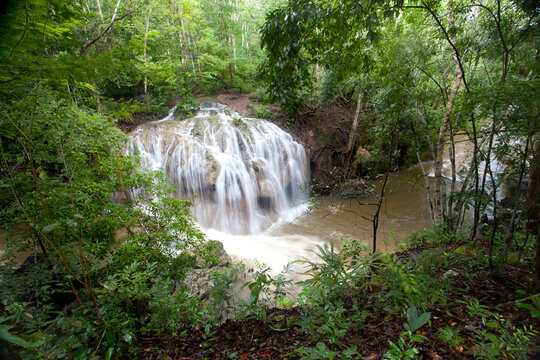 A hotspring waterfall cascades into the cold waters below at Finca Del Paradios near Rio Dulce, Guatemala.