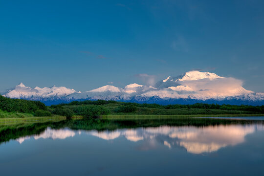 Sunset the first week of summer in Denali National Park, Alaska, casts a soft light on the summits of Mt. McKinley and the Alaska Range, reflecting in Reflection Pond.
