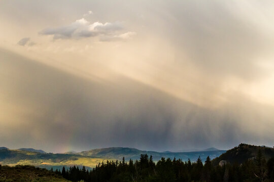 Light shining on rain showers broken up by the Teton Mountains produce a subtle rainbow in Grand Teton National Park, Wyoming.