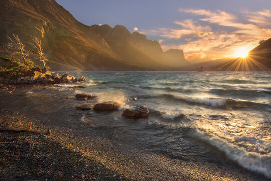 Fierce winds provoke crashing waves on the shore of St. Mary's Lake at sunset.