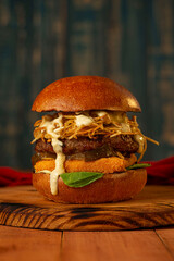 hamburguesa con queso apanado pepinillos y salsa tartara sobre bandeja de madera