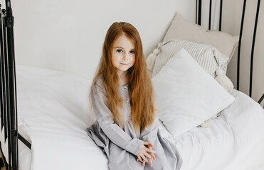 little red haired girl sitting in a country house on a bed, summer vibes concept