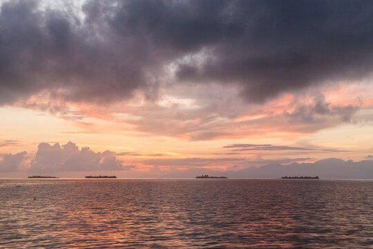 Four small islands of the Cayos Cochinos (Pig Keys) archipelago rise from the Caribbean at sunrise, Honduras.
