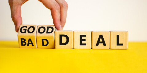 Good or bad deal symbol. Businessman turns wooden cubes and changes words 'bad deal' to 'good deal'. Beautiful yellow table, white background, copy space. Business and good or bad deal concept.