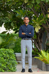Handsome African businessman outdoors at rooftop garden with arms crossed