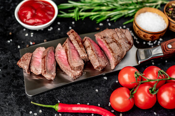 chopped grilled beef steak on a knife on a stone background