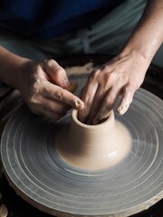 Young female master working on a potter’s wheel, creates clay dishes, view from above.