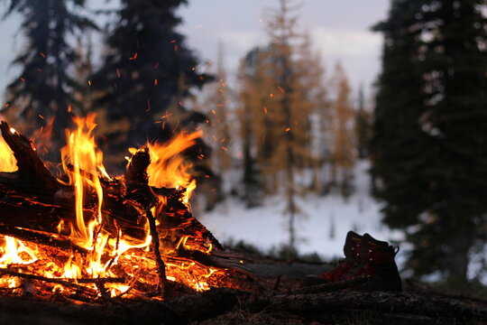 Hiking boots dry out next to a campfire in the wilderness
