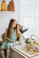 little red haired girl is sitting in the kitchen of a country house with duckling bathing in sink, summer vibes concept