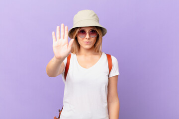 young traveller tourist woman looking serious showing open palm making stop gesture