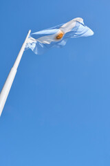 Argentine flag flying on a flagpole on a sunny day with clear skies