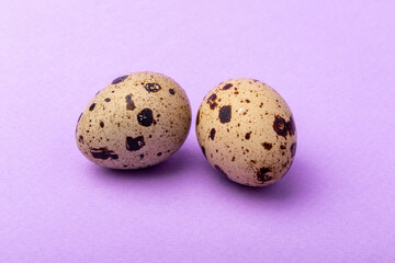 Fototapeta premium two quail eggs on a solid purple background close-up