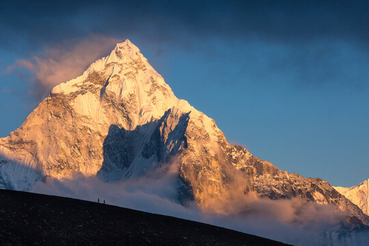 Two hikers on a ridge below Ama Dablam give scale to the massive peak in Nepal's Khumbu region.