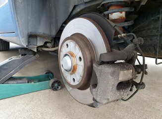 Close up of a car disc brake with a jack during car maintenance. Close up of disc brake of a car lifted on a jack.