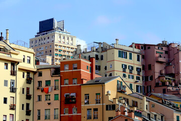 Genoa, Italy. Wide view of colorful houses in Genoa historic city center against a contemporary building and a blue sky in the San Agostino hill.