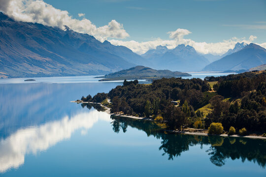 High-noon sun on the high peaks of the Southern Alps creates mirror-like reflections on Lake Wakatipu near Glenorchy in New Zealand's South Island.