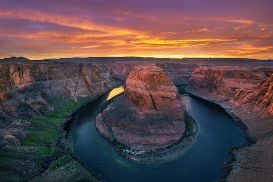 Epic sunset light gives a warm glow to the canyon walls around lake Powell at Horseshow Bend.