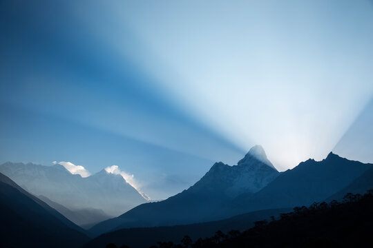 The peaks of Nuptse, Everest, Lhotse, and Ama Dablam and a large beam of light as viewed from the village of Tengboche in Nepal.