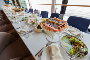served table with cold appetizers with a dish with Japanese rolls before the banquet
