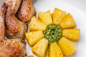 Modern restaurant dish of roasted quail legs decorated with pineapple slices. pesto and asparagus
