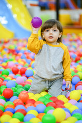 Fototapeta na wymiar Creative development of children. The kid plays with colored balls in the children's development center.