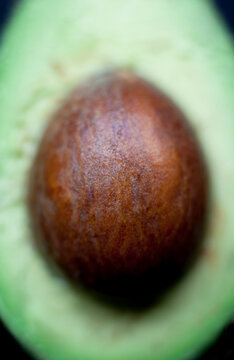 An avocado cut in half with selective macro focusing on the seed.