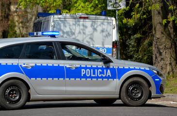 Radiowóz polskiej policji na patrolu w śródmieściu miasta.  Jedzie jezdnią. 