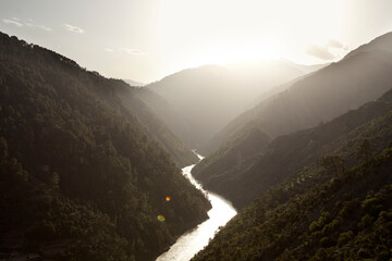 An unknown river in Kashmir, India with a sun setting over the mountains in the background