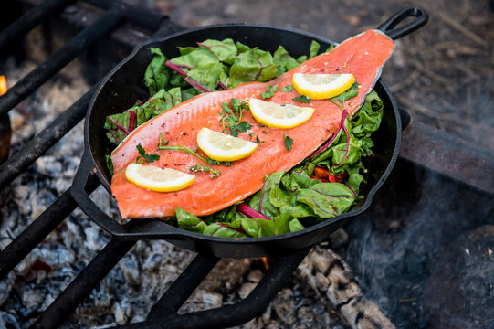Cooking salmon fillets over an open fire.