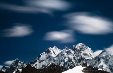 A telephoto view with motion blur of the clouds from Cuyoc Pass looking at the Peaks from tall right to left: Siulu Grande, Jurau, Sarapo in the Cordillera Huayhuash of the Andes Mountains in Peru.