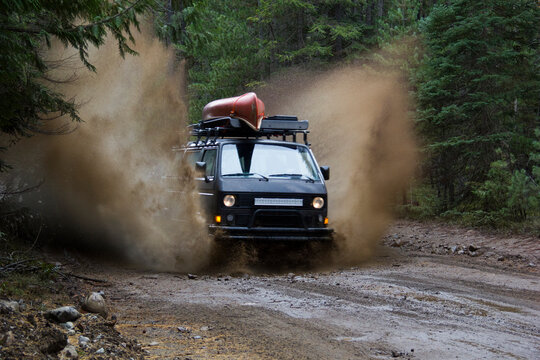 A Volkswagen Synchro van charges through a mud puddle on a dirt back road.